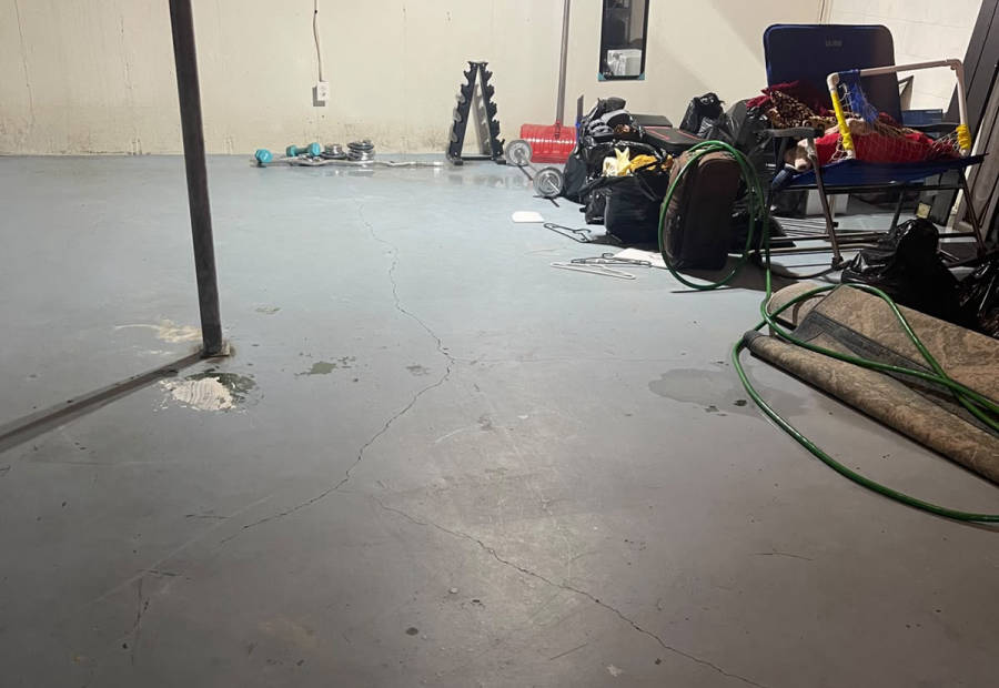 Basement floor cluttered with items and water stains before a Cleanse Co clear-out